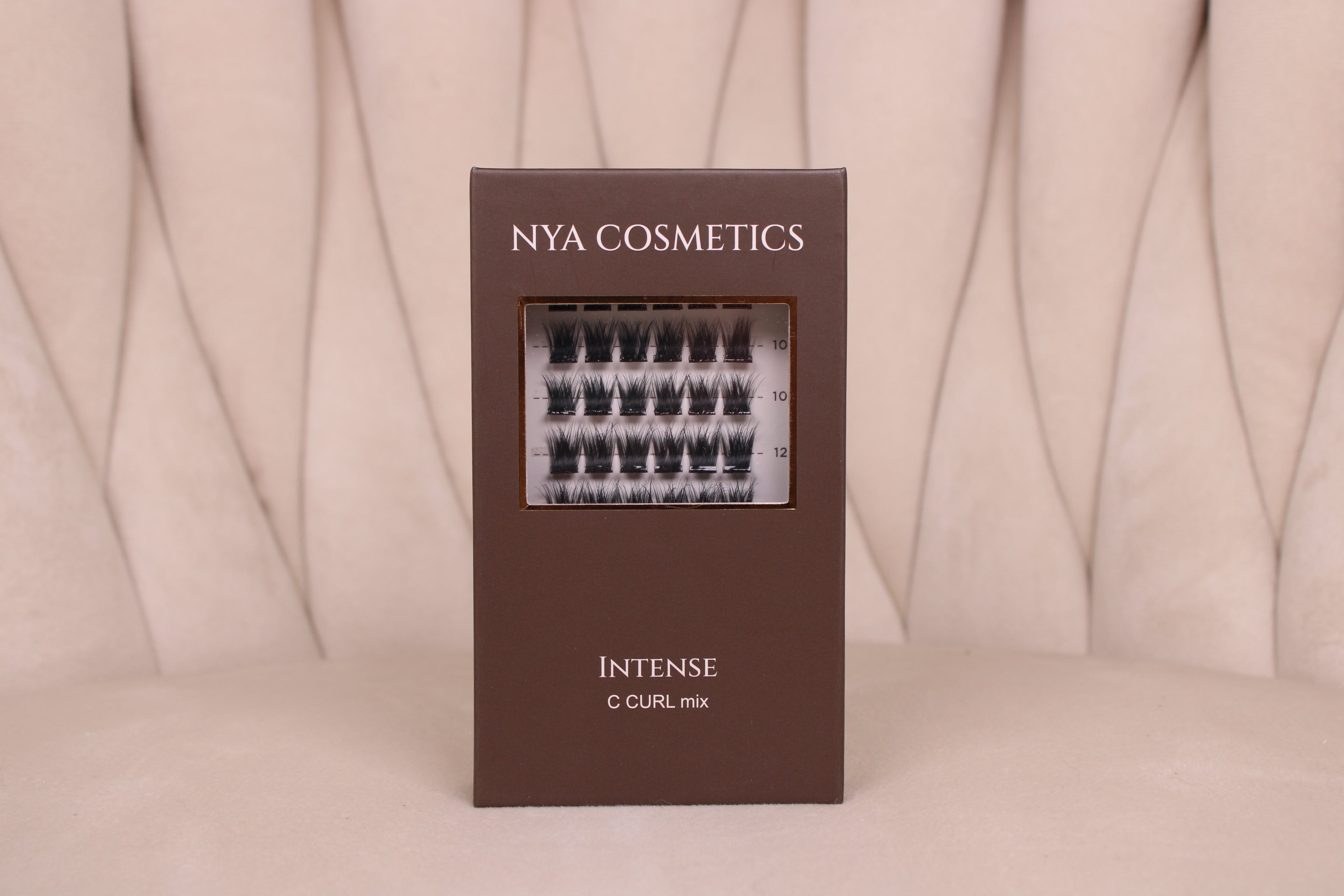Boîte de faux cils auto-adhésifs NYA Cosmetics gamme Intense C Curl mix sur fond beige neutre nouvelle collection 2026