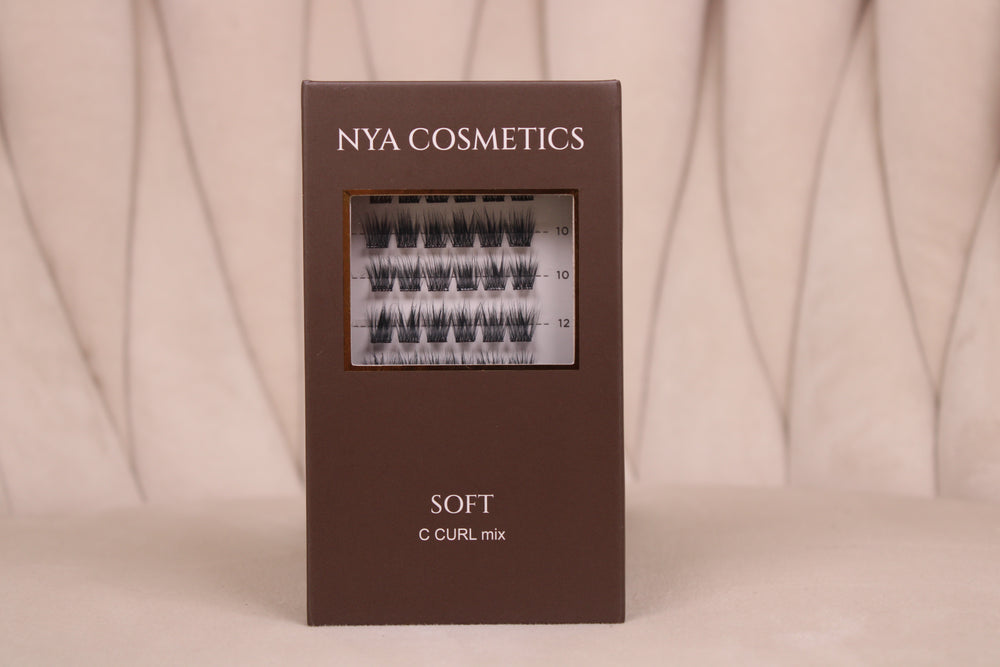 Boîte de faux cils auto-adhésifs NYA Cosmetics gamme Soft C Curl mix sur fond beige neutre nouvelle collection 2026