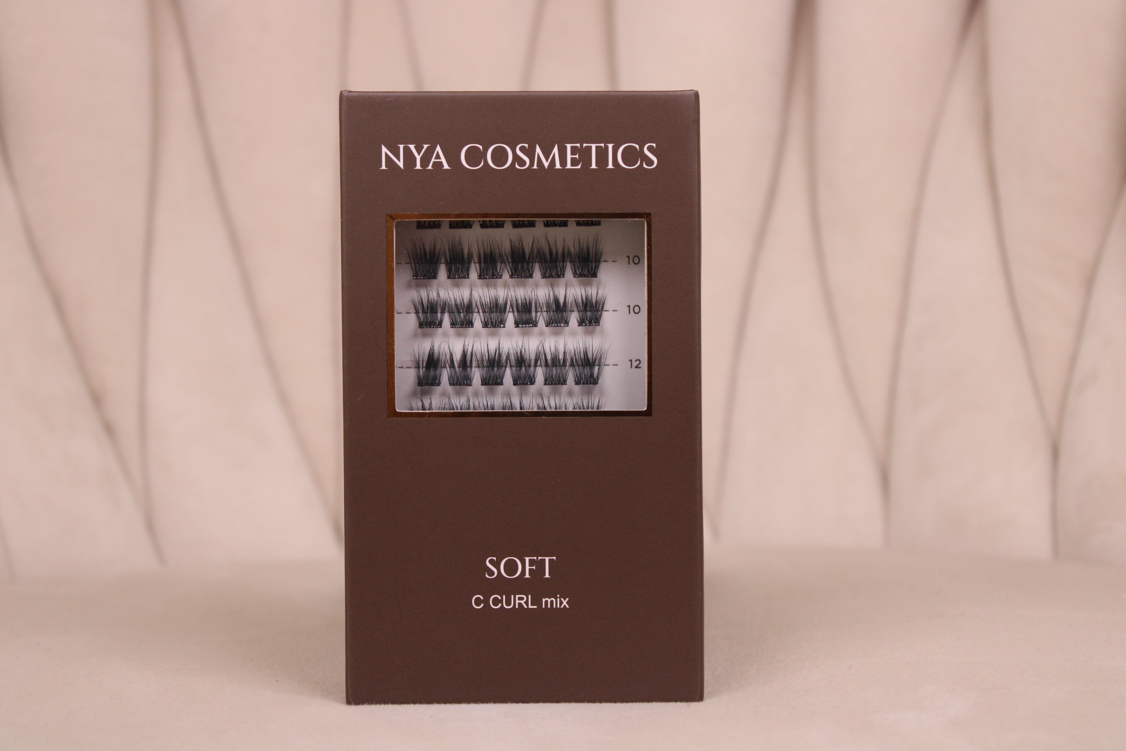 Boîte de faux cils auto-adhésifs NYA Cosmetics gamme Soft C Curl mix sur fond beige neutre nouvelle collection 2026