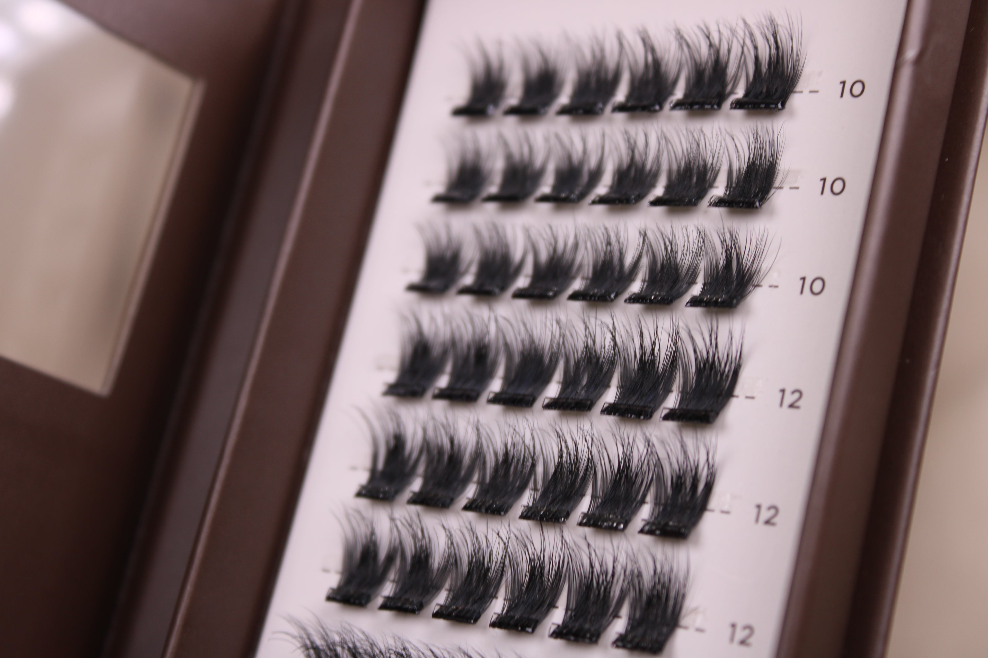 Gros plan sur les clusters de faux cils auto-adhésifs NYA Intense montrant le volume et la densité des bouquets en longueurs 10mm et 12mm nouvelle collection